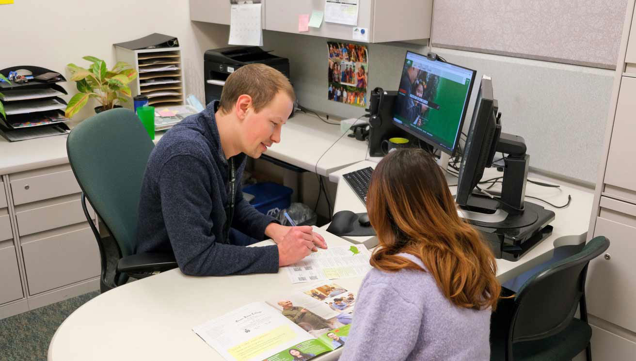 male advisor behind a desk helping female student