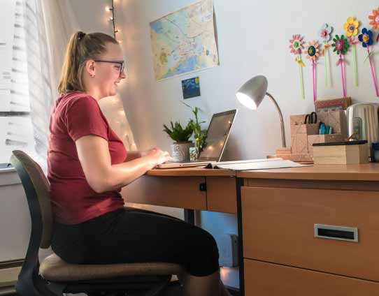 a young woman working at desk in her dorm