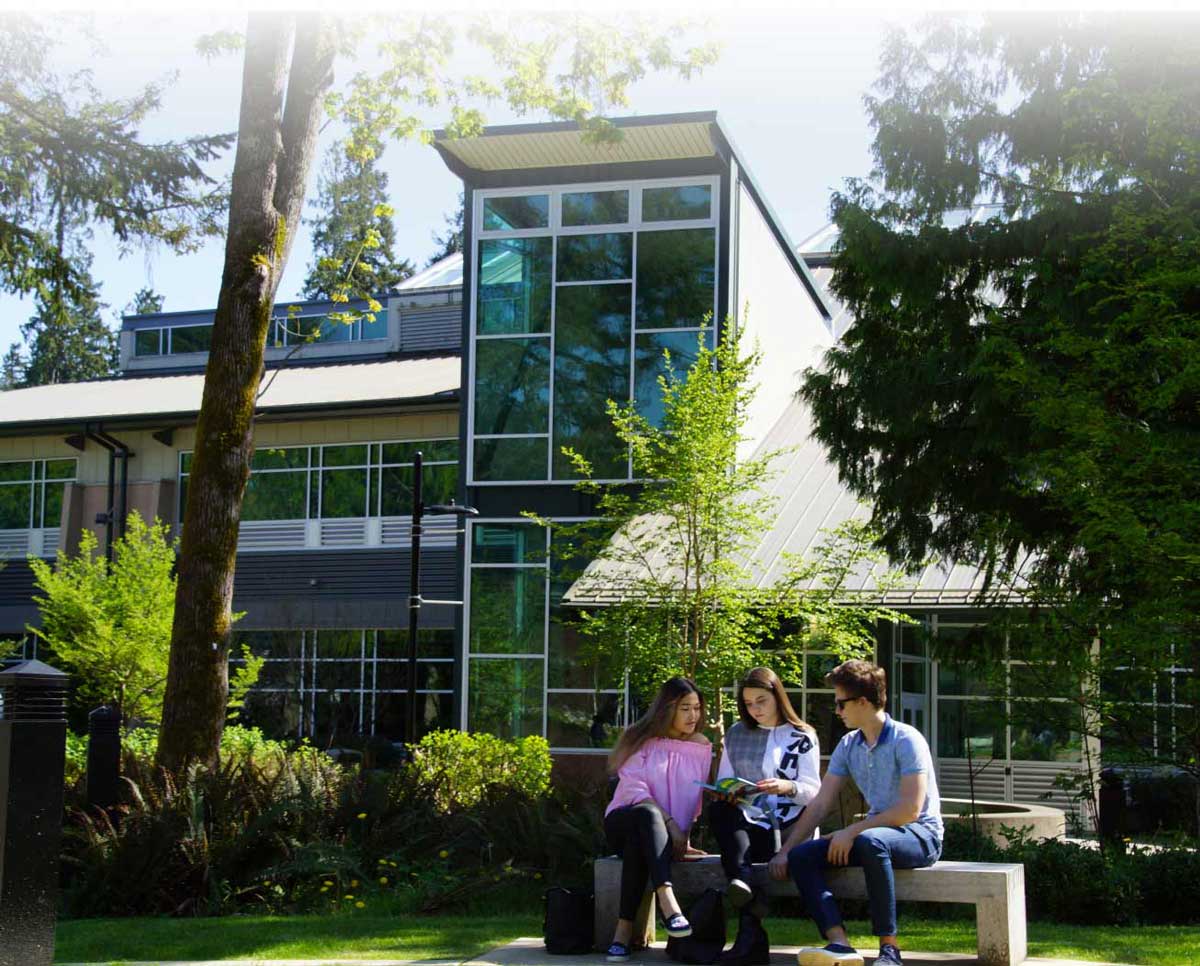 students on a bench in front of large modern building